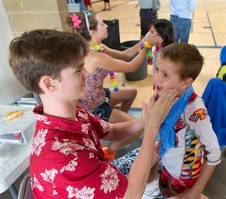 Michael Myers and Catherine Krigbaum slather Hubbard Sports Camp campers in sunscreen before going outside. Photo by Daniel Friedman.