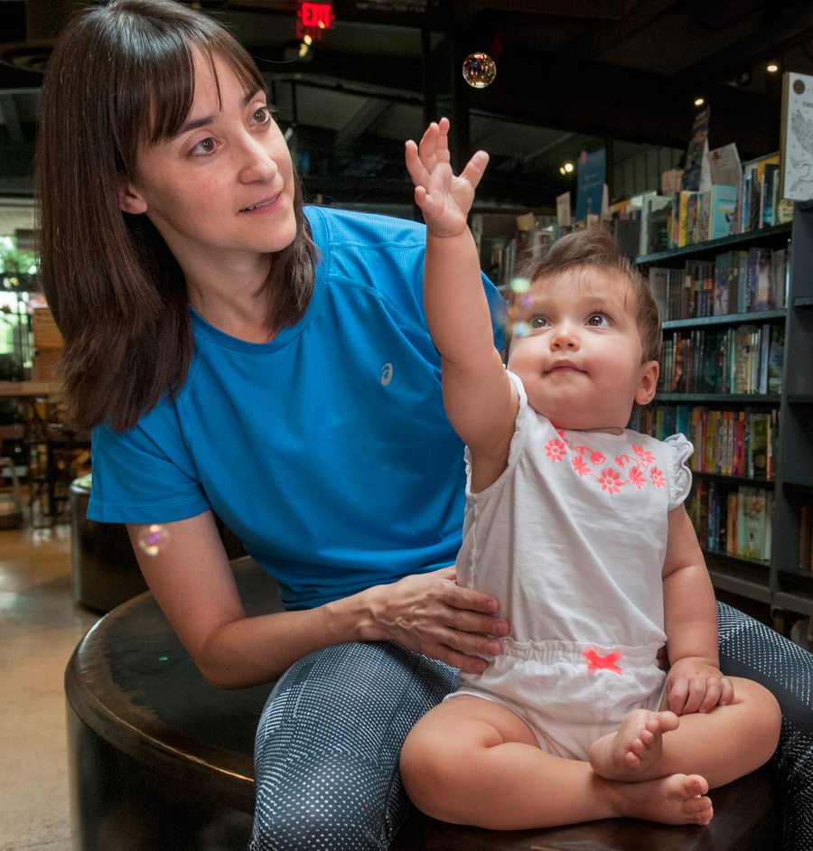 Lola Barrera, 11 months, her mom, Jackie Johnson, try to pop bubbles while participating in Baby Time at Changing Hands in Phoenix.