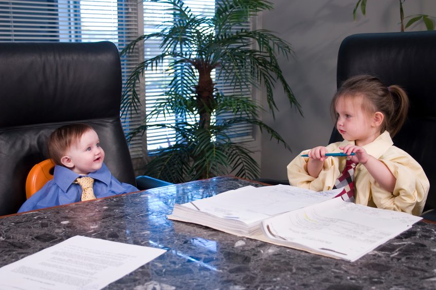 Two young children (girls) pretending to have a business meeting. Dressed in men's shirts and ties discussing some legal documents.