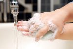 Close-up view of child scrubbing hands under faucet