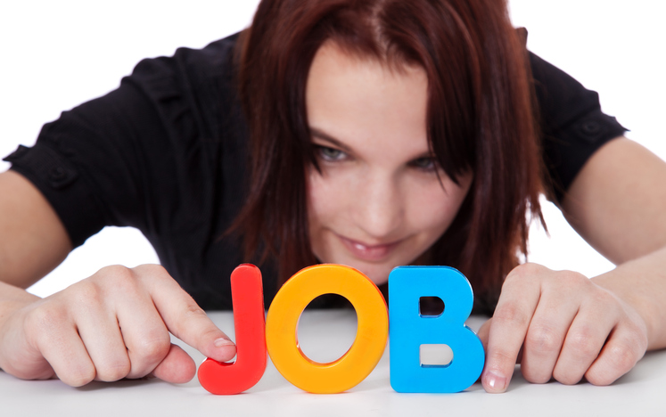 Teenage girl building the term job out of colorful letters. Selective focus on hands and term in foreground. All on white background.
