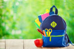 Full School backpack with apple on wooden and nature background.