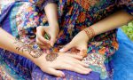 young woman mehendi artist painting henna on the hand