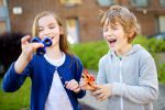 Two funny friends playing with fidget spinners on the playground. Popular stress-relieving toy for school kids and adults.