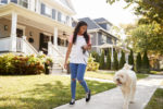 Girl Walking Dog Along Suburban Street