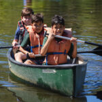 Campers have a great time canoeing on a lake at Friendly Pines Camp in Prescott.